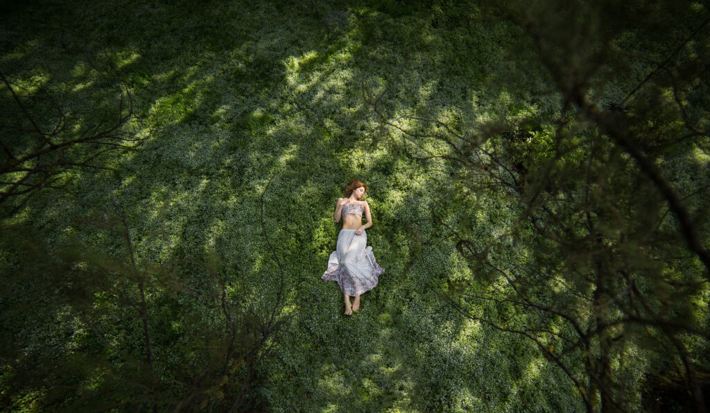Femme allongée au coeur d’une forêt vue du ciel